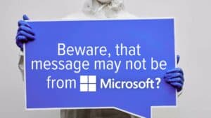 Person Holding a Blank Blue and White Signage. Image text: Beware, that message may not be from Microsoft