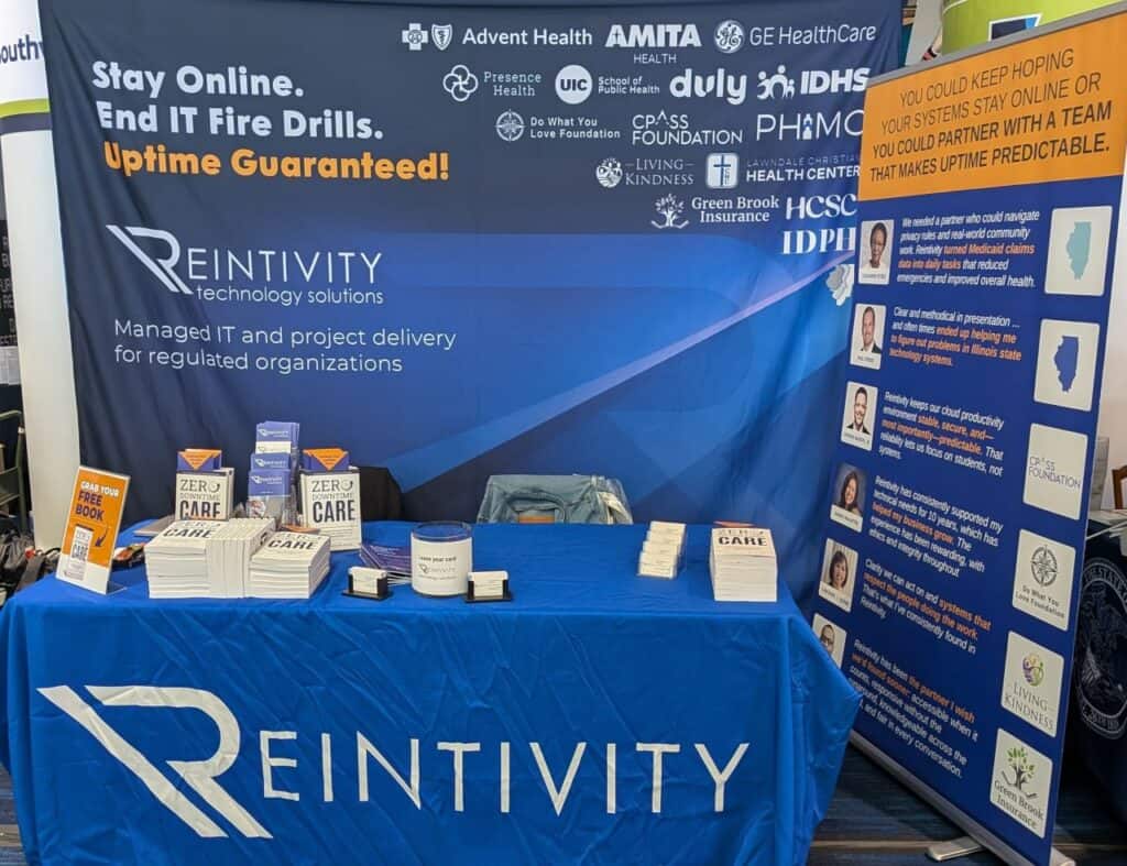 Reintivity exhibit booth at The Exchange 2026 featuring messaging about staying online, ending IT fire drills, and achieving uptime, with materials on managed IT, security, and workflow improvements for regulated organizations.